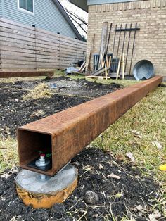 a wooden box sitting on top of a pile of dirt next to a brick building