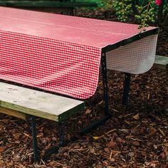 a red and white checkered table cloth on a picnic bench