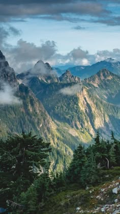 the mountains are covered in clouds and trees