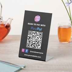 there is a card with a qr code on it next to a cup of tea