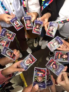 a group of people standing around each other holding up cards with pictures on them in the middle