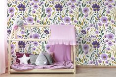 a child's bed with purple and yellow flowers on the wall next to it