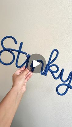 someone is holding up the word stinky in front of a white wall with blue lettering