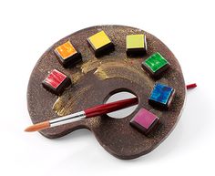 a paintbrush and some chocolates on a brown palette with colored squares around it