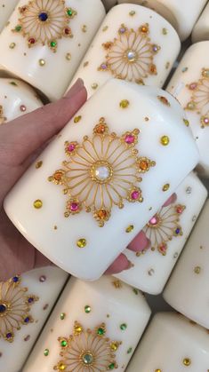 a hand is holding some white candles with gold and jewels on them as if they were made out of tea lights