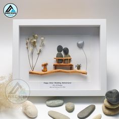 some rocks and stones are arranged in a shadow box with an image of two people sitting on a bench