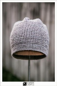 a knitted hat sitting on top of a wooden stand