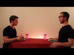 two men standing next to each other at a table with plates of food on it