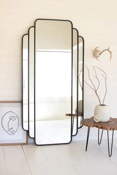 a mirror sitting on top of a wooden table next to a vase and potted plant