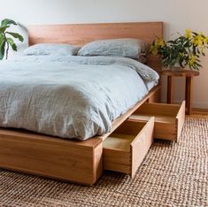 a bed sitting on top of a wooden platform next to a vase with yellow flowers