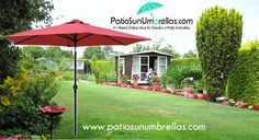 a red umbrella sitting in the middle of a lush green field next to trees and flowers