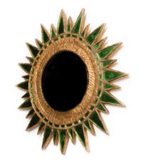 a green and gold sunburst shaped mirror on a white wall