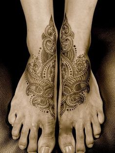 two feet with henna tattoos on them and one has a flower design on it