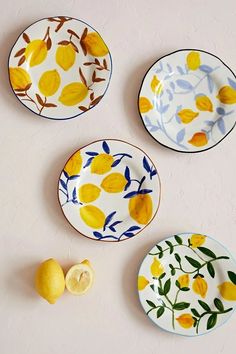 three plates with lemons and leaves painted on them next to a slice of lemon