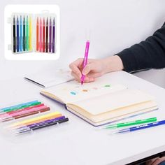 a person sitting at a desk with colored pencils and an open notebook in front of them