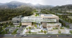 an aerial view of a large building surrounded by trees and mountains with cars parked on the street