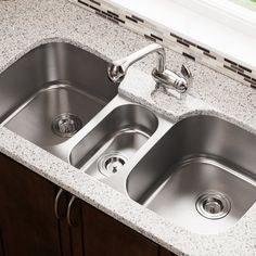 two stainless steel kitchen sinks in a granite countertop