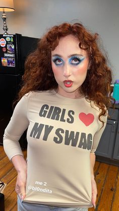 a woman with red hair and blue makeup is wearing a t - shirt that says girls my swag