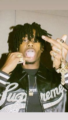 a young man with dreadlocks making a face while holding his hands up to his mouth