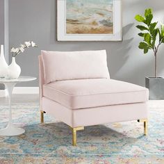 a pink chair sitting on top of a rug next to a vase with flowers in it