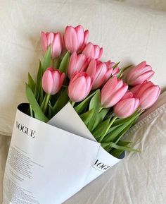 a bouquet of pink tulips sitting on top of a bed