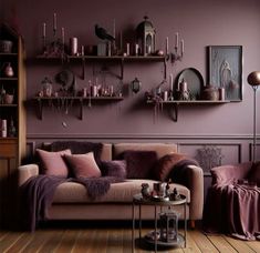 a living room with purple walls and furniture in the corner, including a couch that has pillows on it