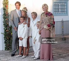 a group of people standing next to each other in front of a white wall with flowers on it