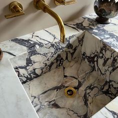 a marble sink with gold faucet handles in a white and black bathroom area