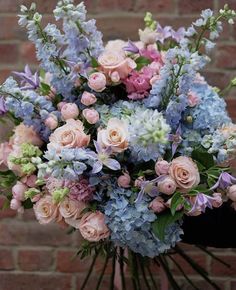 a bouquet of pink and blue flowers in front of a brick wall