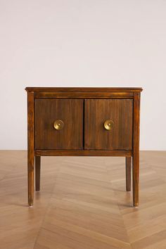 a small wooden table with two drawers on one side and gold knobs on the other