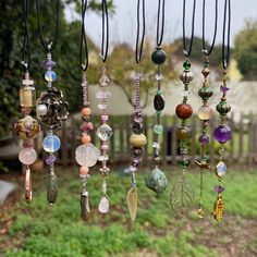 a bunch of different colored beads hanging from a line on a string in front of a fence