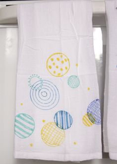 two kitchen towels hanging on the side of a refrigerator door with colorful balls and circles printed on them