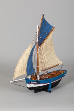 a model sailboat with blue sails on a gray background