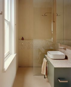 a bathroom with a sink, mirror and shower in it's center wall next to a window