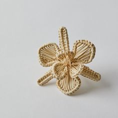 a woven flower brooch sitting on top of a white surface