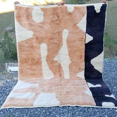 two rugs sitting on top of gravel in front of a tree and grass field