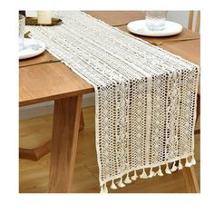 a table runner with tassels on it sitting on top of a wooden table