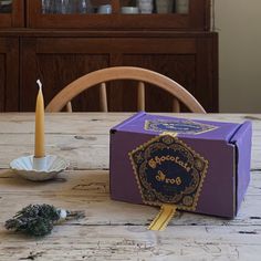 a candle sits on a table next to a purple box with the word chocolate st louis