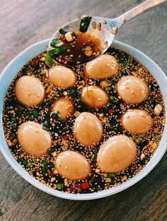 a bowl filled with food on top of a wooden table next to a metal spoon