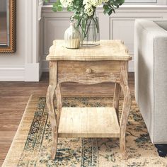 a living room with a couch, coffee table and flower arrangement on the end table