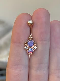 a woman's hand holding an opal and diamond navel ring