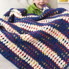 a young boy is smiling while holding a crocheted blanket