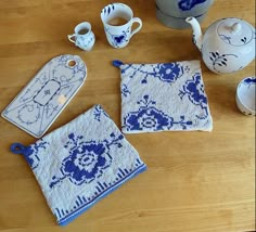 a wooden table topped with blue and white dishes next to teapots, cups and saucers