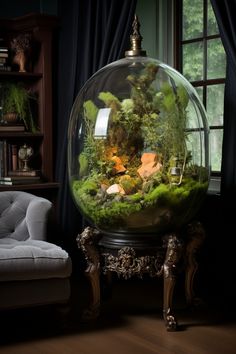 a fish bowl filled with plants and rocks on top of a wooden table next to a chair