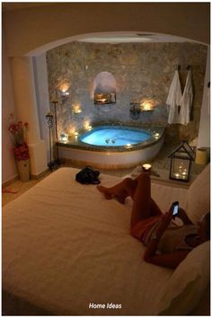 a woman laying on top of a bed in front of a jacuzzi tub