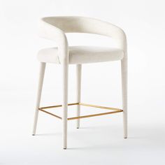 an upholstered stool with a gold frame and foot rest in front of a white background