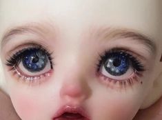 a close up of a child's face with blue eyes and long eyelashes on her head