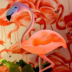 a pink flamingo standing in front of a wallpapered with flowers and birds