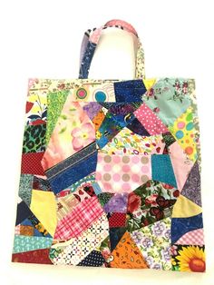 a multicolored patchwork shopping bag is displayed on a white surface with the handles down