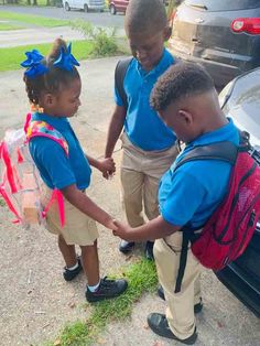 two young children are shaking hands in front of a car